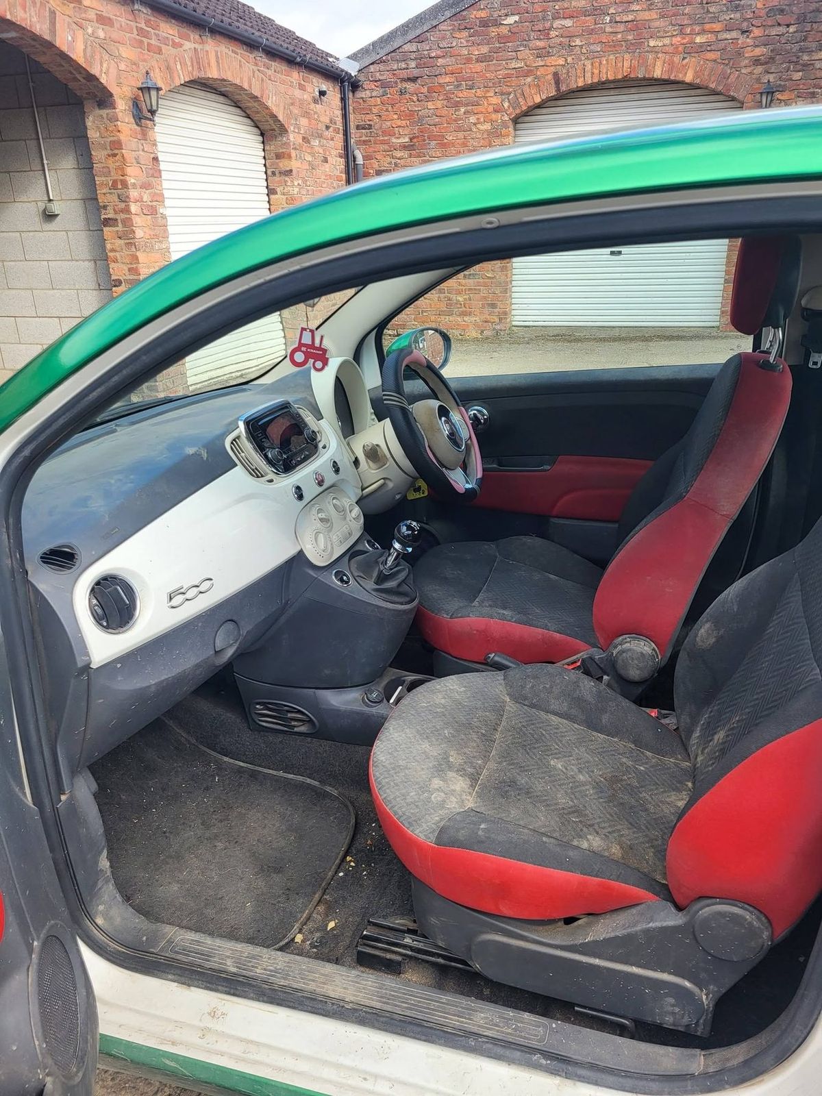 Small car interior before valeting, seats and carpets grey with dust and debris in the footwell